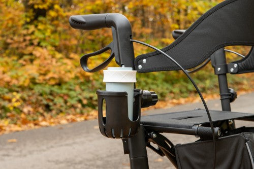 Black stroller cup holder with a white cup against a blurred natural background