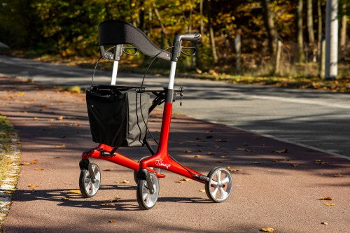 Red scooter with a black bag on a paved path in a park