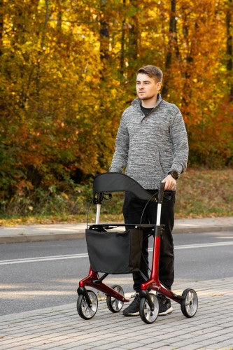 Man using a rollator on a paved path with autumn foliage in the background